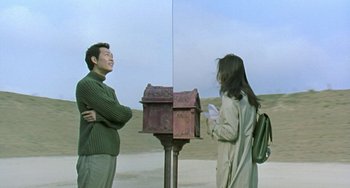 Movie still from “Il Mare” (2000), directed by Hyun-seung Lee – A man and a woman standing next to a mailbox; Medium shot, Over the shoulder angle