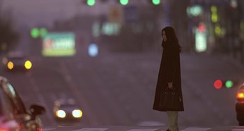 Movie still from “Il Mare” (2000), directed by Hyun-seung Lee – A woman is standing on the side of the street; Wide shot, Low angle