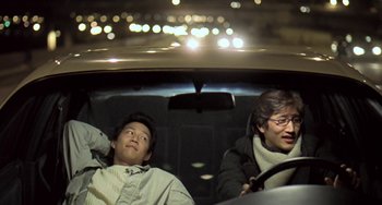 Movie still from “Il Mare” (2000), directed by Hyun-seung Lee – Two people sitting in the back seat of a car at night; Medium shot, Low angle