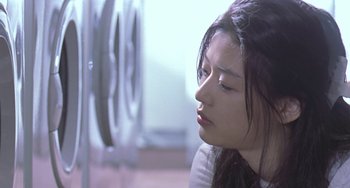 Movie still from “Il Mare” (2000), directed by Hyun-seung Lee – A woman sitting in front of a washing machine; Close Up shot, Low angle