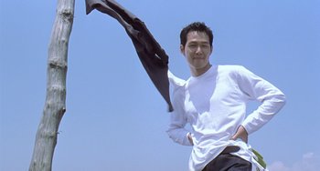 Movie still from “Il Mare” (2000), directed by Hyun-seung Lee – A man holding onto a kite in the air; Medium shot, Low angle