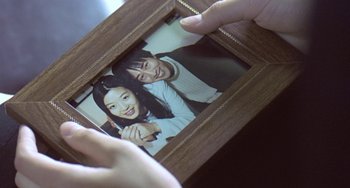 Movie still from “Il Mare” (2000), directed by Hyun-seung Lee – A person is holding a picture of a man and a woman; Extreme Close Up shot, Over the shoulder angle