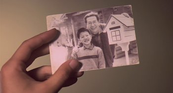 Movie still from “Il Mare” (2000), directed by Hyun-seung Lee – A person holding a picture of a man and a boy; Extreme Close Up shot, High angle