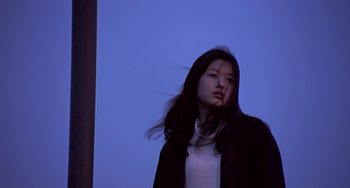 Movie still from “Il Mare” (2000), directed by Hyun-seung Lee – A woman standing in front of a blue sky; Medium shot, Low angle