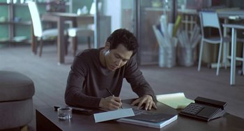 Movie still from “Il Mare” (2000), directed by Hyun-seung Lee – A man sitting at a table writing on a piece of paper; Medium shot, High angle