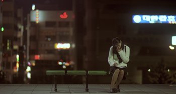 Movie still from “Il Mare” (2000), directed by Hyun-seung Lee – A woman sitting on a bench talking on a cell phone; Wide shot, High angle