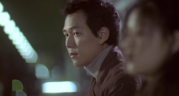 Movie still from “Il Mare” (2000), directed by Hyun-seung Lee – A person wearing a suit and tie; Close Up shot, Over the shoulder angle