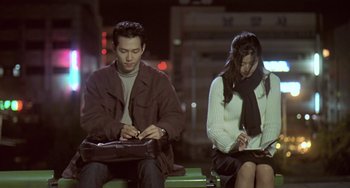 Movie still from “Il Mare” (2000), directed by Hyun-seung Lee – A man and a woman sitting next to each other; Medium shot, Low angle