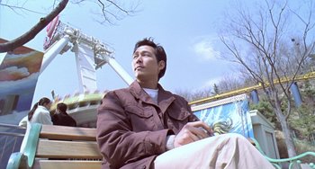 Movie still from “Il Mare” (2000), directed by Hyun-seung Lee – A man sitting on top of a wooden bench; Medium shot, Low angle