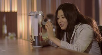Movie still from “Il Mare” (2000), directed by Hyun-seung Lee – A woman is looking at a jar on a table; Close Up shot, Low angle