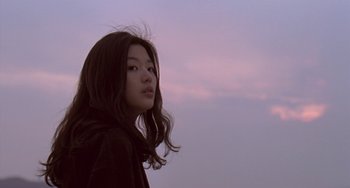 Movie still from “Il Mare” (2000), directed by Hyun-seung Lee – A woman with long black hair standing in front of a purple sky; Close Up shot, Low angle