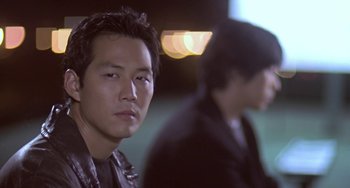 Movie still from “Il Mare” (2000), directed by Hyun-seung Lee – A man in a black jacket is looking at the camera; Close Up shot, Over the shoulder angle