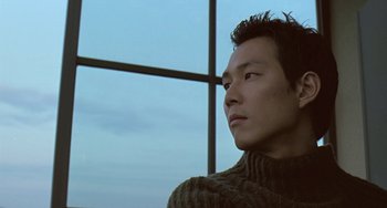 Movie still from “Il Mare” (2000), directed by Hyun-seung Lee – A man in a sweater looking out of a window; Close Up shot, Low angle