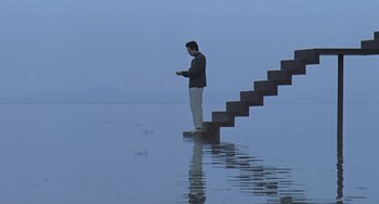 Movie still from “Il Mare” (2000), directed by Hyun-seung Lee – A man standing on a platform in the middle of the water; Wide shot, Low angle