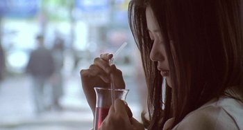 Movie still from “Il Mare” (2000), directed by Hyun-seung Lee – A woman holding a straw and a glass of liquid; Extreme Close Up shot, Over the shoulder angle