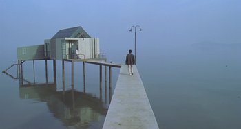 Movie still from “Il Mare” (2000), directed by Hyun-seung Lee – A man standing on a pier next to the water; Extreme Wide shot, Low angle