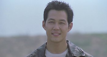 Movie still from “Il Mare” (2000), directed by Hyun-seung Lee – A man with a leather jacket smiles for the camera; Close Up shot, Low angle