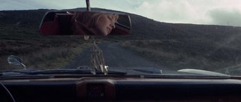 Movie still from “Images” (1972), directed by Robert Altman – A woman looking out of a car's rear view mirror; Close Up shot, Low angle