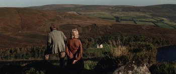 Two people standing on a hill looking at a house