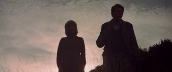 Movie still from “Images” (1972), directed by Robert Altman – A man and a woman standing next to each other in a field; Medium shot, Low angle