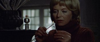 Movie still from “Images” (1972), directed by Robert Altman – A woman lighting a candle in a dark room; Close Up shot, Low angle