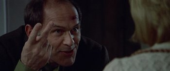 Movie still from “Images” (1972), directed by Robert Altman – An older man looking at the camera in a dark room; Close Up shot, Over the shoulder angle