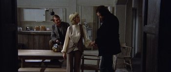 Movie still from “Images” (1972), directed by Robert Altman – A man and a woman holding hands in front of another man; Medium shot, Over the shoulder angle