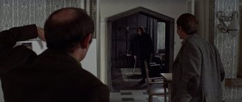 Movie still from “Images” (1972), directed by Robert Altman – A man standing in front of an open door; Medium shot, Over the shoulder angle
