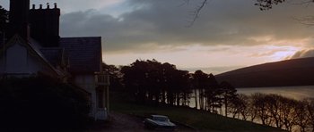 Movie still from “Images” (1972), directed by Robert Altman – A car parked on the side of a road near a lake; Extreme Wide shot, Low angle