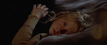 Movie still from “Images” (1972), directed by Robert Altman – A young girl laying on a bed looking sad; Close Up shot, High angle