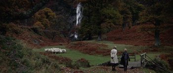 Movie still from “Images” (1972), directed by Robert Altman – A woman in a white coat standing in front of a waterfall; Extreme Wide shot, High angle