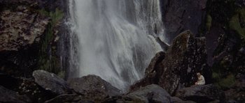 Movie still from “Images” (1972), directed by Robert Altman – A large waterfall is pouring into a body of water; Extreme Wide shot, Low angle