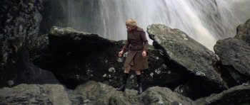 Movie still from “Images” (1972), directed by Robert Altman – A woman standing on top of a rock near a waterfall; Wide shot, High angle