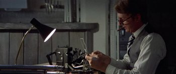 Movie still from “Images” (1972), directed by Robert Altman – A man sitting in front of a laptop computer on top of a desk; Close Up shot, Low angle