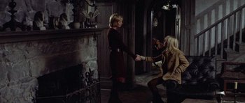 Movie still from “Images” (1972), directed by Robert Altman – Two women are shaking hands in front of a fire place; Wide shot, High angle