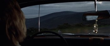 Movie still from “Images” (1972), directed by Robert Altman – A view from inside a car looking out a window at a mountain range; Wide shot, High angle
