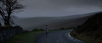 Movie still from “Images” (1972), directed by Robert Altman – A person walking down a road near a hill; Extreme Wide shot, Low angle