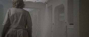 Movie still from “Images” (1972), directed by Robert Altman – A man standing in a room holding an open umbrella; Medium shot, Low angle