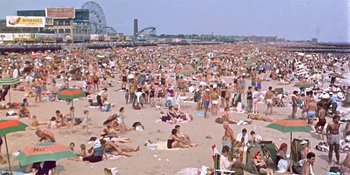 Movie still from “Imitation of Life” (1959), directed by Douglas Sirk – A crowd of people sitting and standing on a beach; Extreme Wide shot, High angle