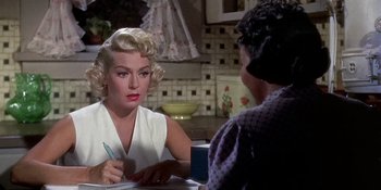 Movie still from “Imitation of Life” (1959), directed by Douglas Sirk – A woman sitting at a table with a pen in her hand; Close Up shot, Over the shoulder angle