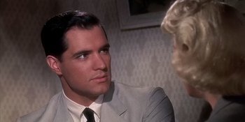 Movie still from “Imitation of Life” (1959), directed by Douglas Sirk – A man wearing a suit and tie talking to a woman wearing a dress suit; Close Up shot, Over the shoulder angle