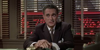 Movie still from “Imitation of Life” (1959), directed by Douglas Sirk – A man wearing a suit and tie sitting at a table; Close Up shot, Over the shoulder angle