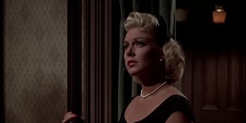 Movie still from “Imitation of Life” (1959), directed by Douglas Sirk – A woman in a black dress and a pearl necklace; Close Up shot, Low angle