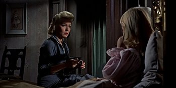 Movie still from “Imitation of Life” (1959), directed by Douglas Sirk – A woman sitting on the ground holding a camera; Medium shot, Over the shoulder angle