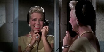 Movie still from “Imitation of Life” (1959), directed by Douglas Sirk – An older woman talking on a phone in front of a mirror; Close Up shot, Low angle