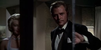 Movie still from “Imitation of Life” (1959), directed by Douglas Sirk – A man wearing a suit and tie standing in front of a wall; Close Up shot, Low angle