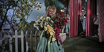 Movie still from “Imitation of Life” (1959), directed by Douglas Sirk – A woman holding a bouquet of flowers in her hands; Medium shot, Low angle