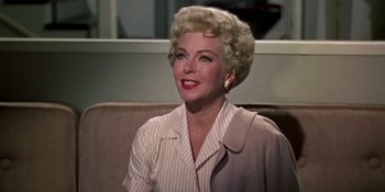 Movie still from “Imitation of Life” (1959), directed by Douglas Sirk – An older woman sitting on a couch in front of a mirror; Close Up shot, Low angle