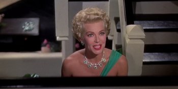 Movie still from “Imitation of Life” (1959), directed by Douglas Sirk – An older woman wearing a necklace and a green dress; Close Up shot, Low angle