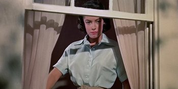 Movie still from “Imitation of Life” (1959), directed by Douglas Sirk – A woman standing in front of a window looking at the camera; Medium shot, Low angle